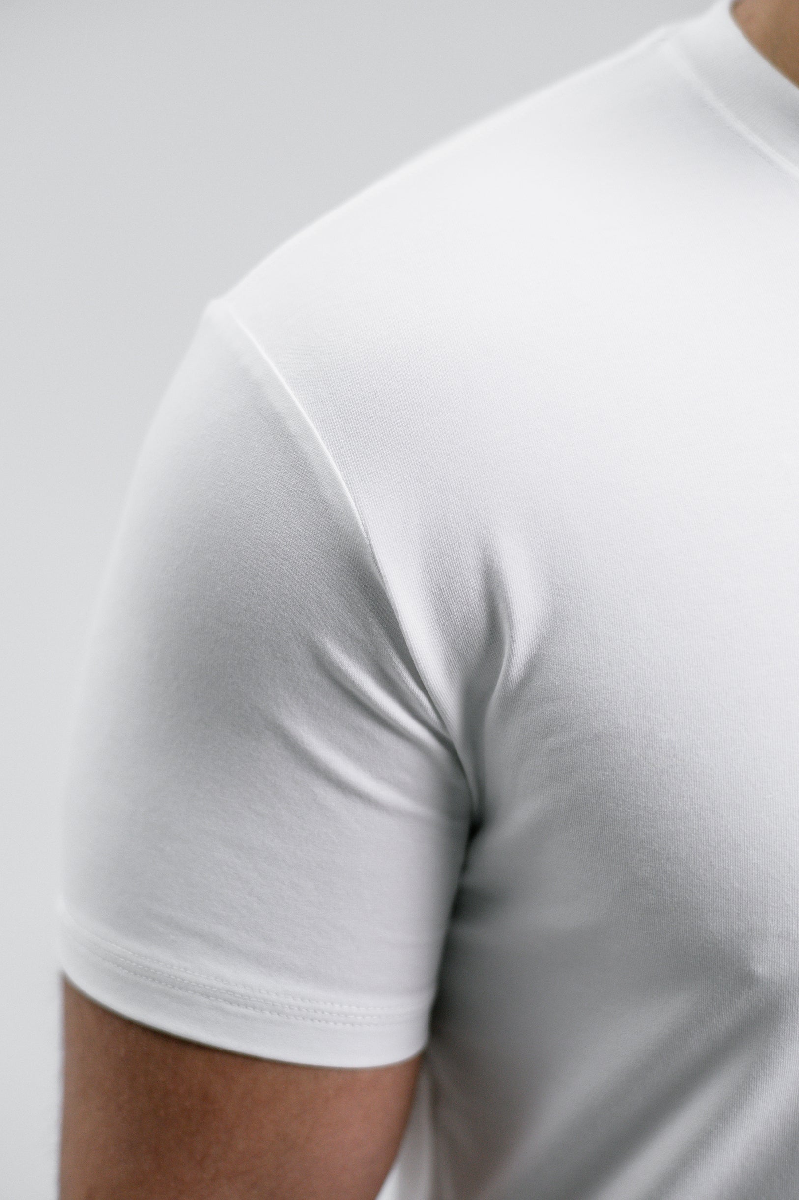 Eine Ärmeldreifachnaht von dem weißen Mens Essentials T Shirt